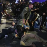 Police drag away people who take part in a protest against Israeli Prime Minister Benjamin Netanyahu